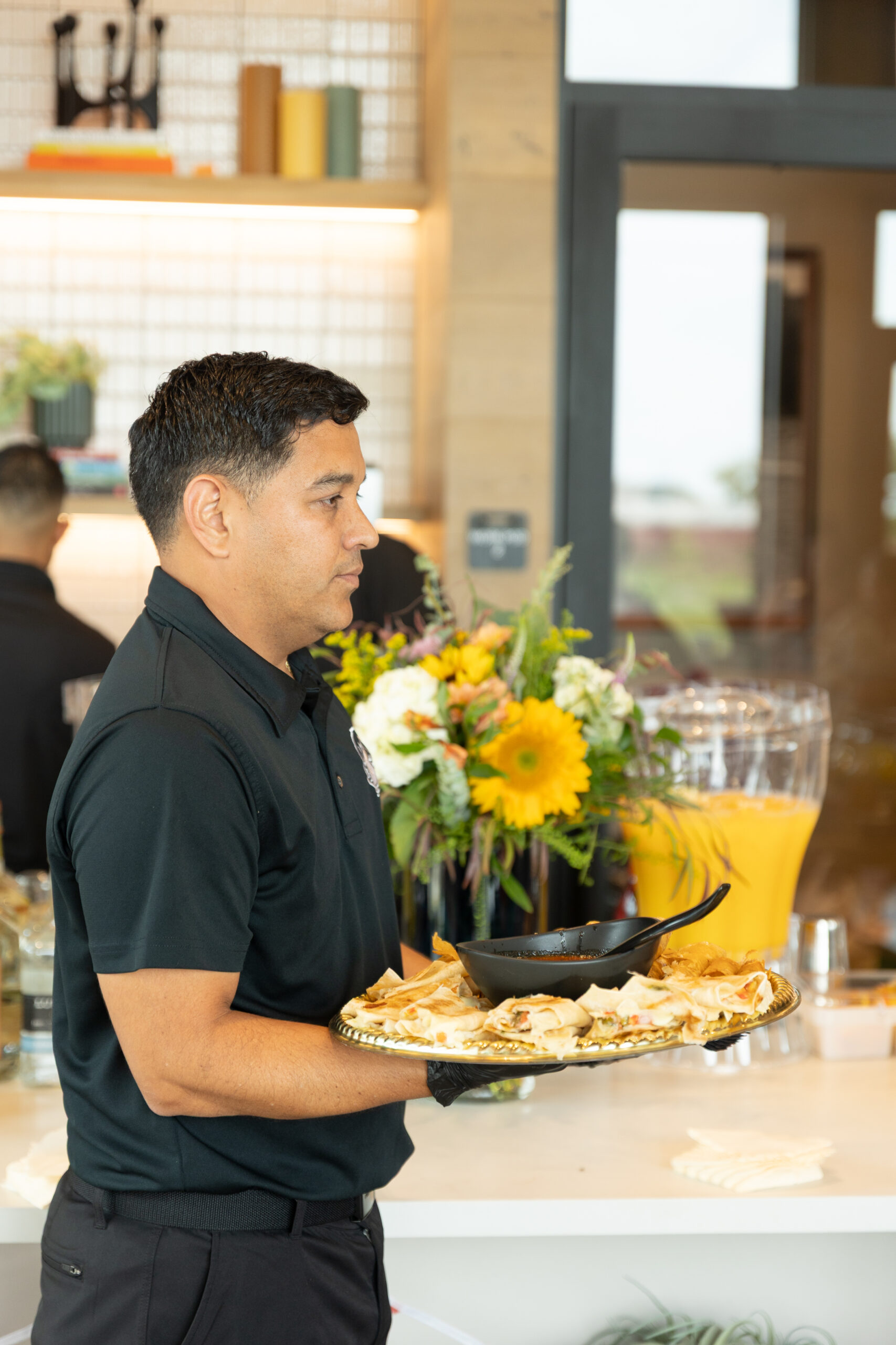 Server holding a tray of appetizer rolls with dipping sauce